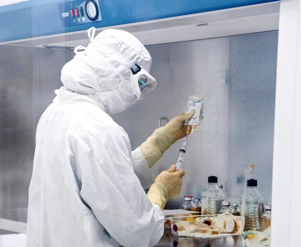 Scientist extracting fluid from medical pouch for testing.