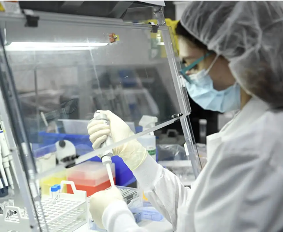 Scientist pipetting fluids into a test rack for sterilization.